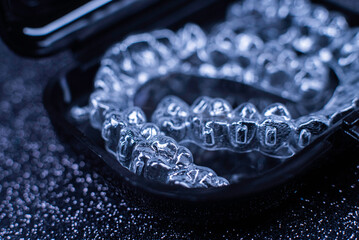 Invisalign transparent aligners rotate in a black container. Plastic removable teeth correction...