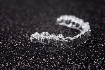 Invisible dental teeth brackets tooth aligners on black background. Plastic braces dentistry retainers to straighten teeth.