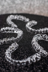 Invisible dental teeth brackets tooth aligners on black background. Plastic braces dentistry retainers to straighten teeth.