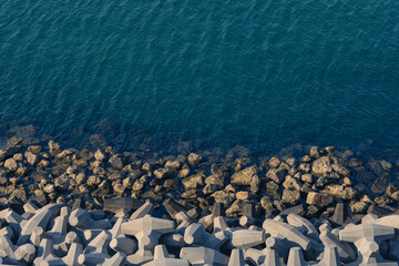 Concrete tetrapods and natural rocks meeting the deep blue sea