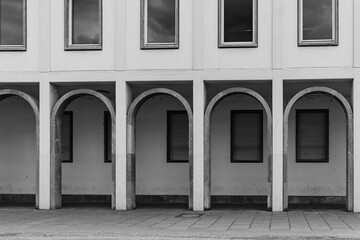 Architectural details of a modern building with arched columns and windows in a city setting during the day