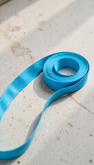 Blue ribbon laying on a surface with sunlight creating shadows  
