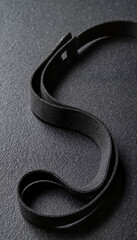 Black elastic band for fitness, twisted on a textured background