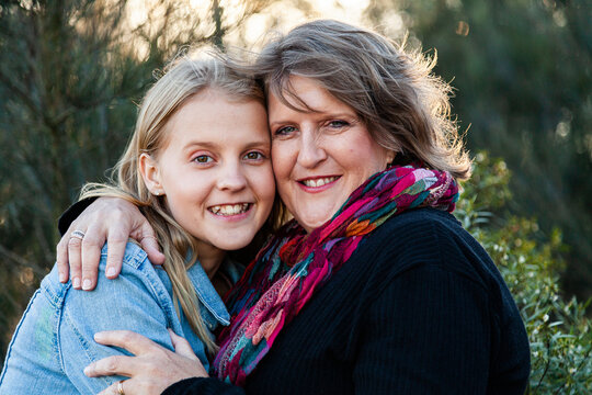 Mother and teen daughter embrace one another in hug