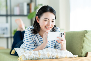 リビングでスマホを見る若い女性