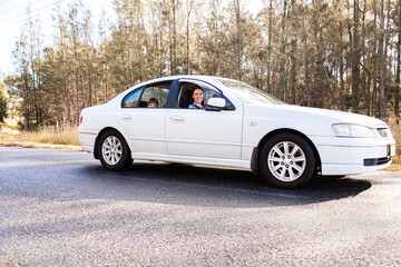 Young female driver driving car with children in back seats on country road