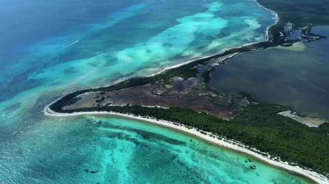 A right-panning aerial video of Punta Sur in Cozumel, Mexico, showcasing the unique land formation with its turquoise waters, white beach, lush greenery, and bordering lagoon.