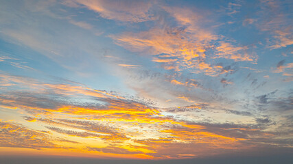 Aerial view A breathtaking view of a coastal city at sunset, with golden hues illuminating the sky and reflecting on the calm ocean. Small islands and boats are visible in the distance.