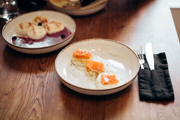 Salted cottage cheese pancakes with greens, with salmon slices and sour cream.