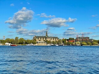 View of Stockholm from a boat, Sweden. View of Stockholm from the water features an elegant historical building, likely the Nordiska Museum, with its intricate roof and spire. 