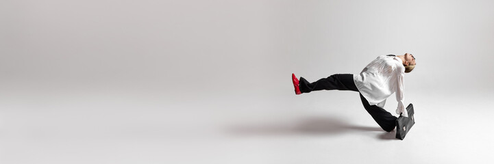 Banner. Young woman with briefcase do huge step to success against white studio background with...