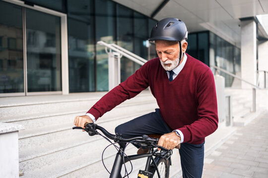 Senior Man Commuting on Bike Near Urban Office Building