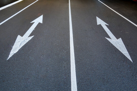 Two traffic arrow symbols on the road surface, pointed at both ends, on a city road in Seattle.