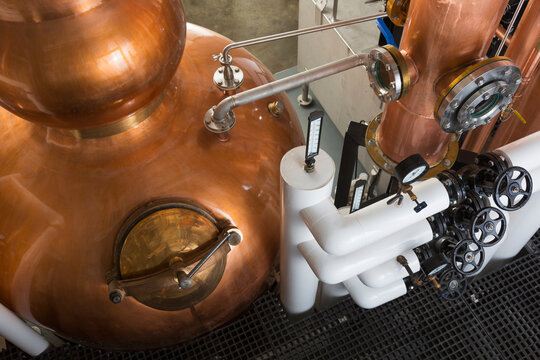 A copper still in a distillery, a large copper chamber and pipework for distilling. 