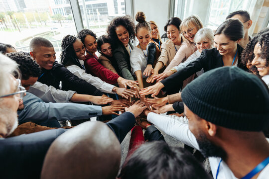 Corporate team with hands united celebrating success and teamwork in modern office environment