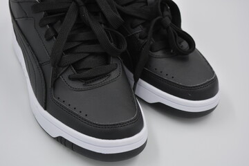 Beautiful, youth sports shoes, black boots with white hard soles are on a white plasti.. Warm half-boots made of leatherette with insulation, synthetic fur, beautiful cotton black laces.