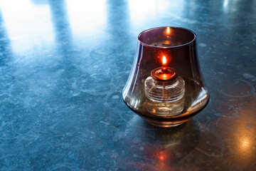 A kerosene table lamp lit on a blue table. 