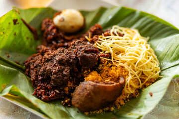 Waakye, local Ghana food made with rice and beans served spaghetti, egg, wele and gari on plantain leaves.