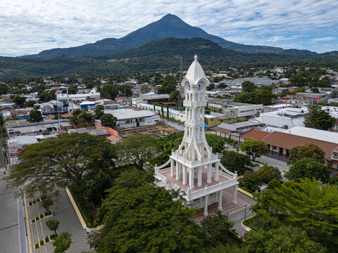 Aerial drone photo of a small tourist town historical center main square with clock observation tower, San Vicente volcano in the background. Sunny day, blue sky. San Vicente, El Salvador.