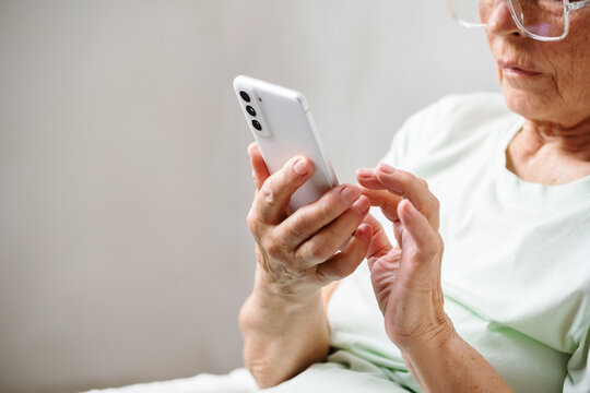 Closeup of elderly female hands hold smart phone, scroll images, messages, texting for networking on app for social media.