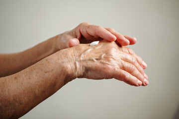 Close-up of elderly woman's hands. Woman applying cream to her hands.