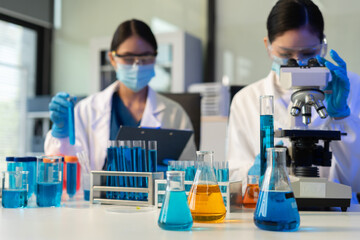 Fototapeta premium Scientist analyzing and dropping a sample into a glassware.