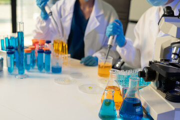 Scientist analyzing and dropping a sample into a glassware.