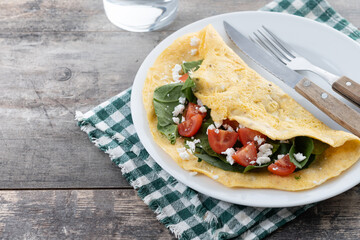 Stuffed omelette with tomatoes and spinach on wooden table