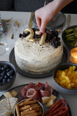 A birthday celebration table with a delicious cake, cupcakes, and tropical fruits.