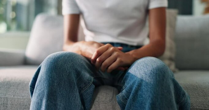 Anxiety, psychology and person fidgeting with hands on sofa with stress or emotions in living room at home. Mental health, worry and leg shake for panic attack with phobia, overthinking or fear.
