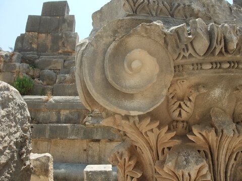 Close-up of a Corinthian column capital with intricate carvings and spiral volutes, part of ancient Greek architecture