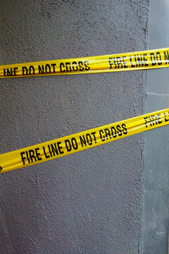 Fire Line Do Not Cross tape, yellow tape with black lettering stretched across a wall.
