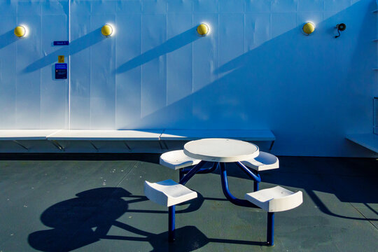 A ferry deck, fixed seating and a round table.