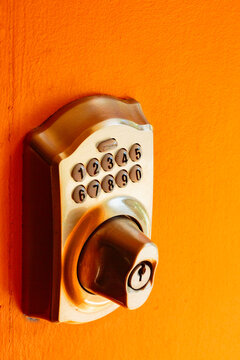 Electronic Door lock and key pad on an orange background, close up.