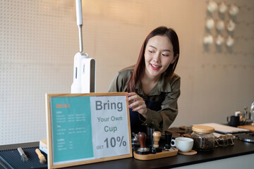 Promoting Eco-Conscious Choices. A barista setting up a sign to encourage customers to bring their own cups for discounts.