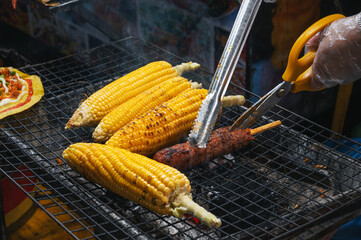 grilled corn and meat sausage grilled on fire at the Asian street night market in Vietnam in Asia