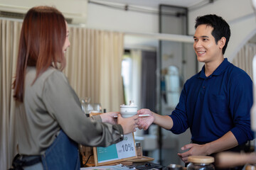 Customer Interaction and Eco-Friendly Initiatives. A barista passing a drink to a customer, emphasizing sustainability.