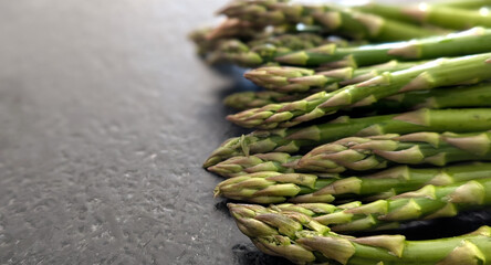 Top view of a fresh organic green asparagus on a dark natural granite stone table. Copy space.