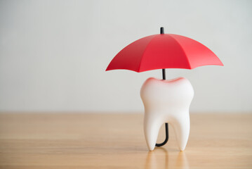 Red umbrella covers white clean tooth on white background copy space. Dental insurance, dental care, tooth protection concept. Dental health insurance is a contract that helps pay for dental care cost © pla2na