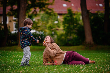 Child Playing Near Parent Blowing Bubbles in Park