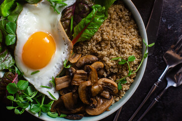 Quinoa with egg, mushrooms and salad in a plate on the table. Bowl