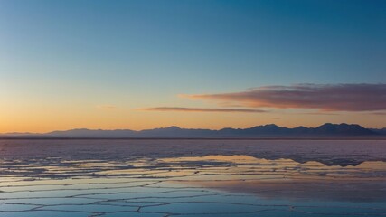 Fototapeta premium A serene landscape at sunset reflecting on a salt flat with distant mountains.
