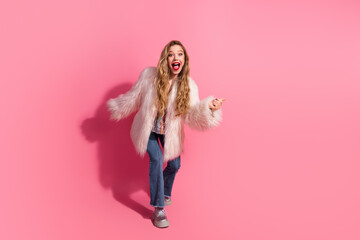 Stylish young woman in pink fur coat expressing excitement against a trendy pink backdrop