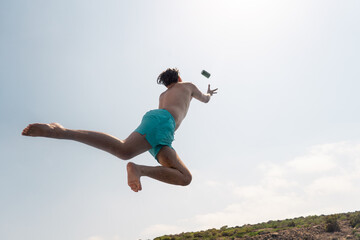 Man jumping into the sea catching a green can in Ayia Napa, Cyprus