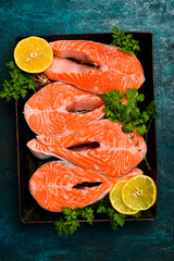 Background of cooking salmon steaks on a metal tray. Dark textured background.
