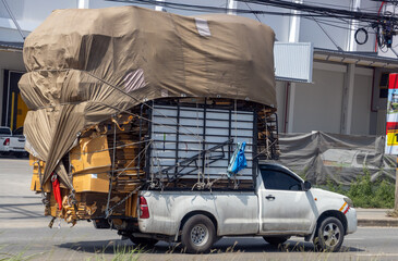 A pick-up truck fully loaded with paper for recycling drives down a city street, Thailand © milkovasa