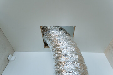 A shiny silver duct protrudes conspicuously from the ceiling, which indicates the presence of a...
