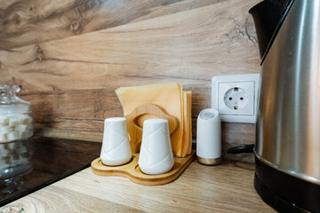 On the kitchen counter, there is a stylish electric kettle placed alongside salt and pepper shakers as well as a neatly arranged napkin holder, all essential items for cooking and dining