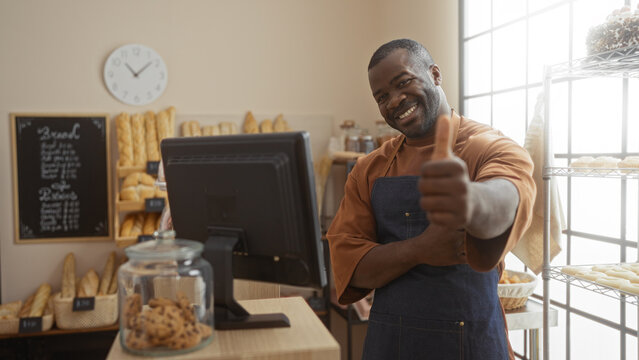 Young man smiling and giving thumbs up in a bakery with fresh bread and cookies visible in the background - Powered by Adobe