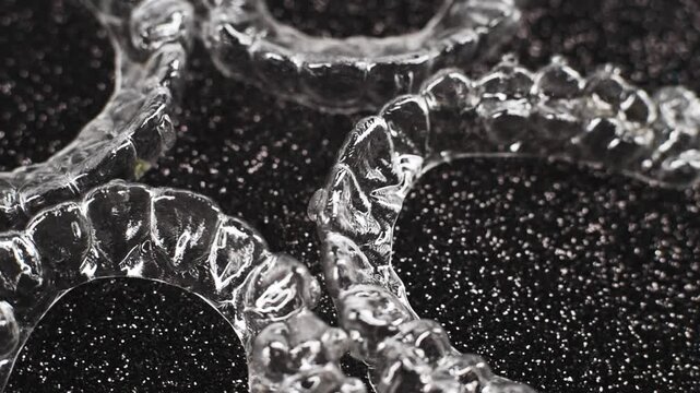 Invisible dental teeth brackets tooth aligners on black background. Plastic braces dentistry retainers to straighten teeth.